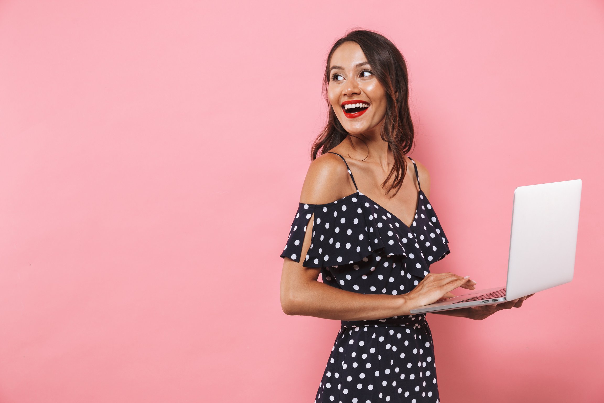 Beautiful Woman Isolated over Pink Background Using Laptop Computer Typing.